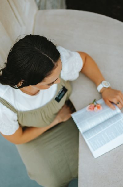 a woman sitting at a table writing on a piece of paper